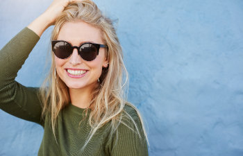 cheerful blonde in sunglasses smiling on blue background, Indian Land, SC